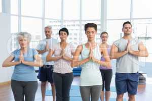 People with eyes closed and joined hands at fitness studio
