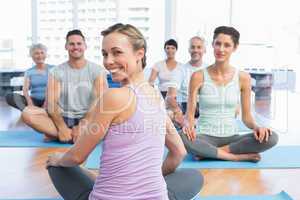 Sporty people sitting on exercise mats at fitness studio