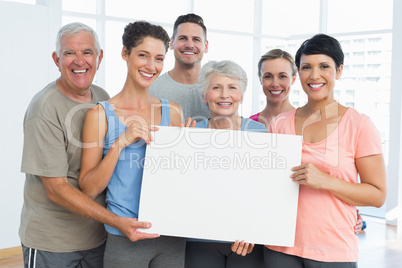 Fit people holding blank board in yoga class