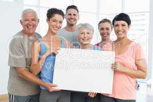 Fit people holding blank board in yoga class