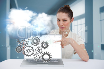 Businesswoman pointing to her laptop showing cogs and wheels