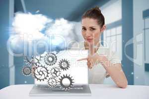 Businesswoman pointing to her laptop showing cogs and wheels