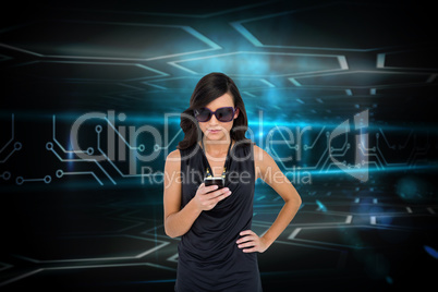 Glamorous brunette using smartphone against circuit board