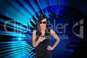 Glamorous brunette using smartphone against blue technology back
