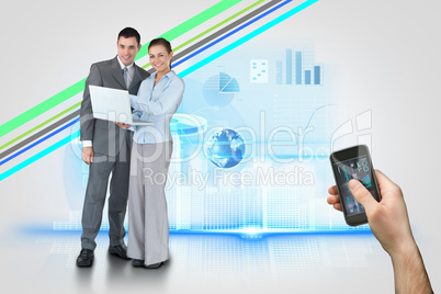 Hand holding smartphone with interface and business partners beh