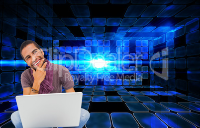 Composite image of thinking man sitting on floor using laptop an