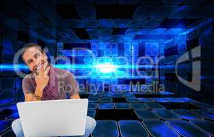 Composite image of thinking man sitting on floor using laptop an