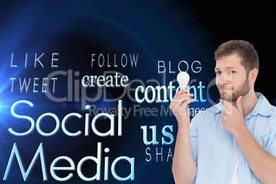 Composite image of handsome model holding a bulb