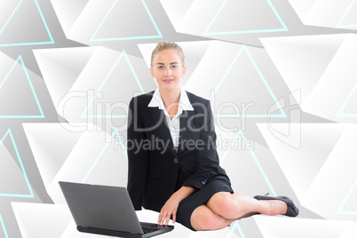 Composite image of businesswoman using laptop