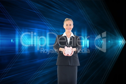 Composite image of happy businesswoman holding a piggy bank