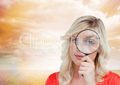 Composite image of fair-haired woman looking through a magnifyin