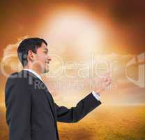 Composite image of smiling asian businessman pointing