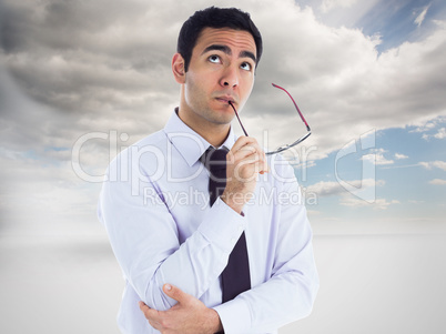 Composite image of thinking businessman holding glasses