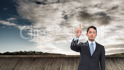 Composite image of serious asian businessman pointing