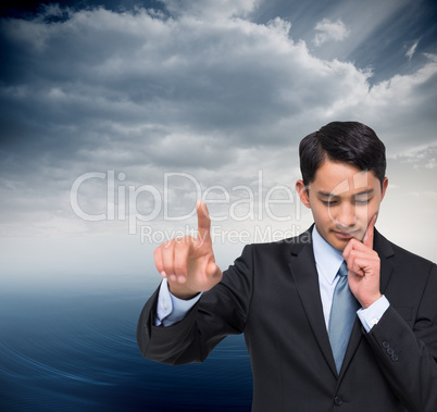 Composite image of thoughtful asian businessman pointing