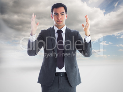 Composite image of unsmiling businessman with arms raised