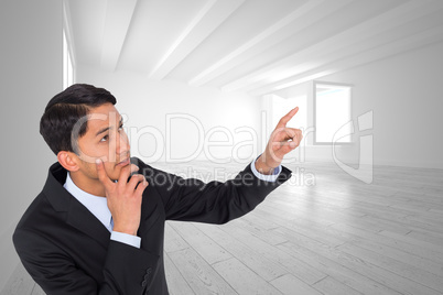 Composite image of thoughtful asian businessman pointing