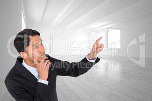 Composite image of thoughtful asian businessman pointing