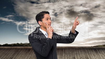 Composite image of thoughtful asian businessman pointing