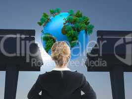 Composite image of businesswoman standing with hands on hips