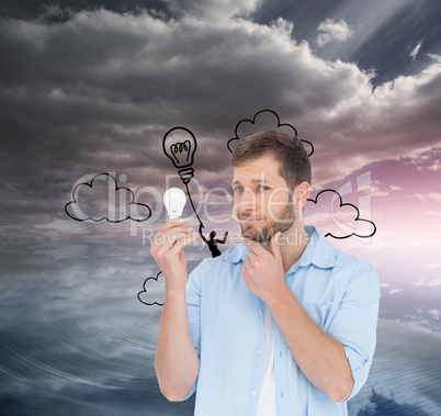 Composite image of handsome model holding a bulb