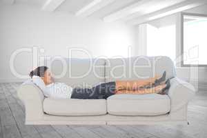 Composite image of smiling business woman lying down on the couc