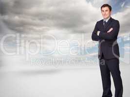 Composite image of young businessman standing cross-armed