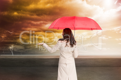 Composite image of businesswoman holding umbrella