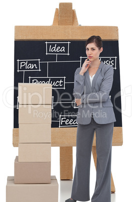 Composite image of thoughtful businesswoman posing with cardboar
