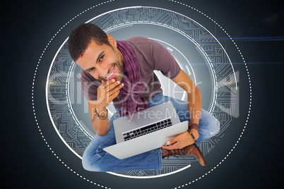 Composite image of thoughtful man sitting on floor using laptop