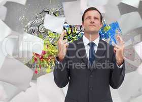 Composite image of serious businessman with fingers crossed is l