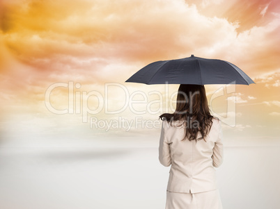 Composite image of rear view of classy businesswoman holding umb