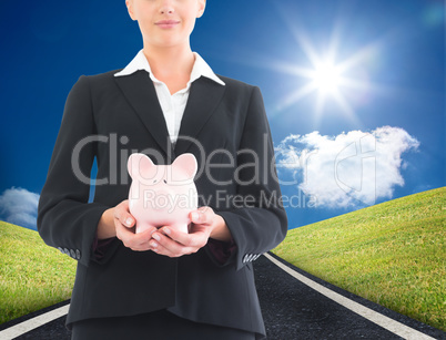 Composite image of businesswoman holding piggy bank