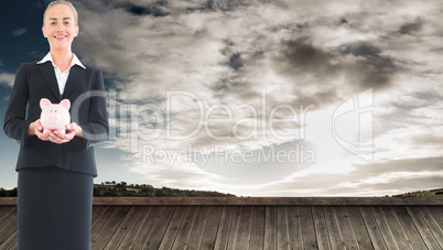 Composite image of businesswoman holding pink piggy bank