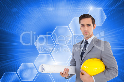 Composite image of serious architect holding plans and hard hat