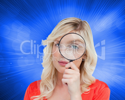 Composite image of fair-haired woman looking through a magnifyin