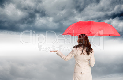 Composite image of businesswoman holding umbrella