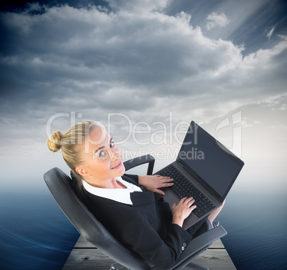 Composite image of businesswoman sitting on swivel chair with la