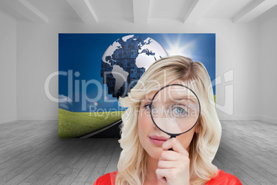 Composite image of fair-haired woman looking through a magnifyin