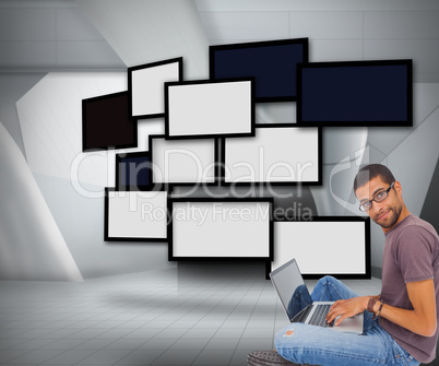 Composite image of man wearing glasses sitting on floor using la