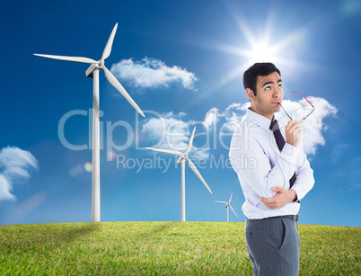 Composite image of thinking businessman holding glasses