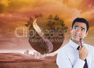 Composite image of thinking businessman holding glasses