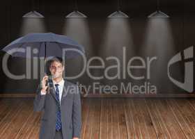 Composite image of happy businessman holding grey umbrella