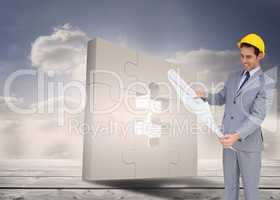 Composite image of smiling architect with hard hat looking at pl