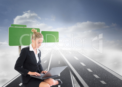 Composite image of businesswoman using laptop