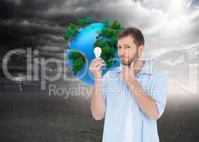 Composite image of handsome model holding a bulb