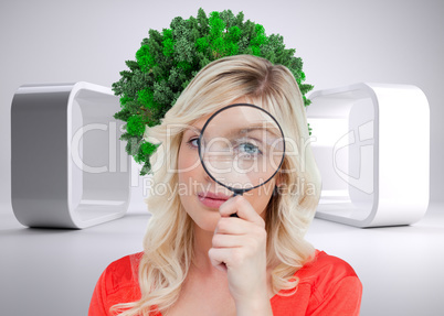 Composite image of fair-haired woman looking through a magnifyin
