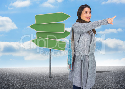 Composite image of smiling brunette wearing winter clothes point