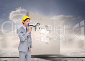 Composite image of young architect yelling with a megaphone