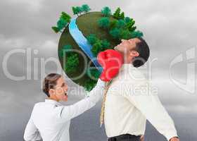 Composite image of businesswoman hitting a businessman with boxi